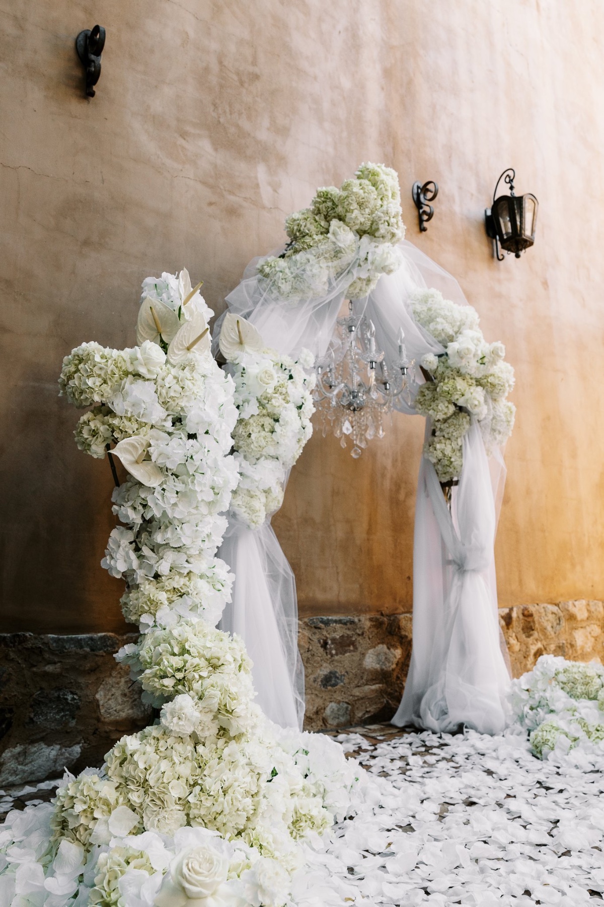 draped wedding ceremony arch with white flowers and chandelier